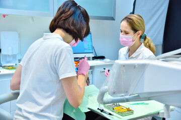 Woman dentist with assistant prepares patient for teeth whitening procedure.