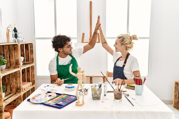 Young artist couple smiling happy high five at art studio.