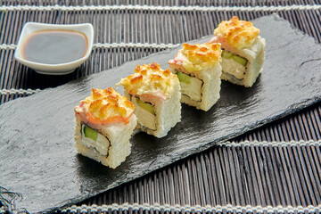 Baked cucumber rolls on a dark stone. Japanese sushi.