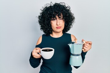 Young middle east woman holding italian coffee maker skeptic and nervous, frowning upset because of problem. negative person.