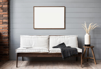 Blank picture frame mockup on gray wall. Artwork in interior design. View of modern scandinavian style interior with sofa and empty canvas for painting or poster on wall. Minimalism concept