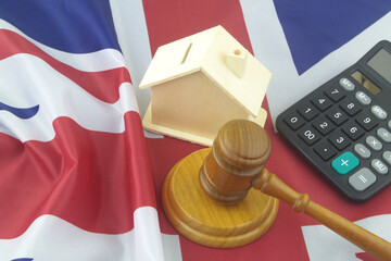 Real estate and legal questions in UK. Wooden gavel, calculator and house model on British flag.