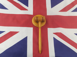 Wooden judge gavel on United Kingdom flag. Laws and court in UK concept.