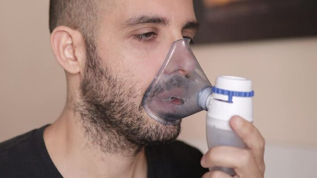 Caucasian man doing inhale treatment for asthma, allergy or cold. Closeup, side