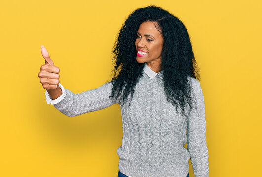 Middle age african american woman wearing casual clothes looking proud, smiling doing thumbs up gesture to the side