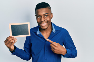 Young african american man holding empty frame smiling happy pointing with hand and finger