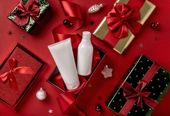 White bottles cosmetic products in red giftbox and on red background. Christmas sale of beauty...