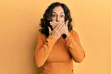 Middle age hispanic woman wearing casual clothes shocked covering mouth with hands for mistake. secret concept.