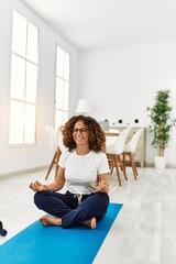 Middle age hispanic woman smiling confident training yoga at home