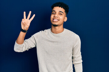 Young african american man wearing casual clothes showing and pointing up with fingers number three while smiling confident and happy.