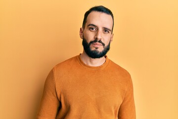 Young man with beard wearing casual winter sweater relaxed with serious expression on face. simple and natural looking at the camera.