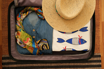 Suitcase preparation for vacation.Summer vacation plan. Summer clothes, straw hats and colorful...