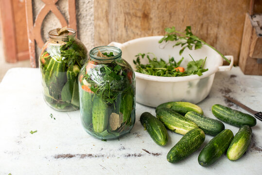 Preparation of canned cucumbers or fermented cucumbers in glass jars. Ingredients for pickling cucumbers. Cucumbers, dill, garlic. Glass jars with pickles. Processing of the autumn harvest. 