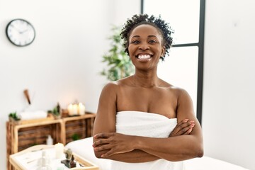 Young african american woman wearing towel standing at beauty center happy face smiling with...