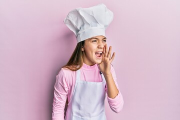 Beautiful brunette little girl wearing professional cook apron and hat shouting and screaming loud...