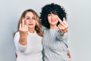 Middle east mother and daughter wearing casual clothes showing middle finger, impolite and rude...