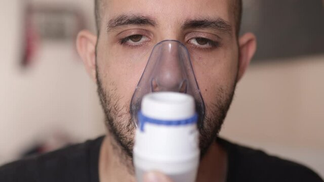 Caucasian man doing inhale treatment for asthma, allergy or cold