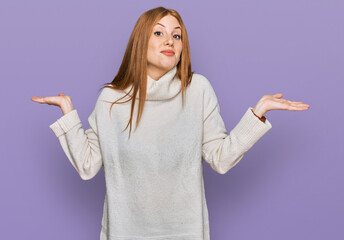 Young irish woman wearing casual winter sweater clueless and confused expression with arms and hands raised. doubt concept.