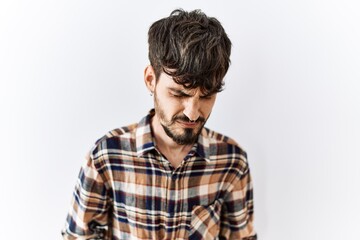 Hispanic man with beard standing over isolated background with hand on stomach because nausea,...