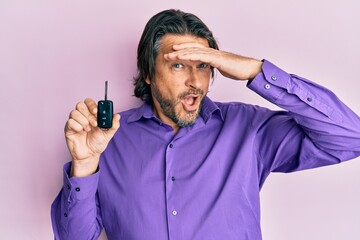 Middle age handsome man holding key of new car stressed and frustrated with hand on head, surprised and angry face