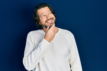 Middle age caucasian man wearing casual clothes looking confident at the camera with smile with crossed arms and hand raised on chin. thinking positive.