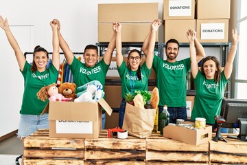 Group of young volunteers smiing happy with fists raised up at charity center.