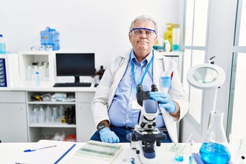 Fototapeta premium Senior caucasian man working at scientist laboratory relaxed with serious expression on face. simple and natural looking at the camera.
