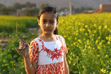 Happy rural Indian girl child standing on the cottage threshold in an Indian village outside her...