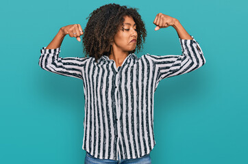 Young african american girl wearing casual clothes showing arms muscles smiling proud. fitness concept.