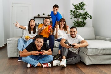 Group of young friends smiling happy playing video game at home.