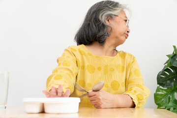 Unhappy Asian senior woman anorexia and say no to ready meals, Elderly home alone and bored food...