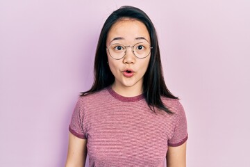 Young chinese girl wearing casual clothes and glasses afraid and shocked with surprise expression, fear and excited face.