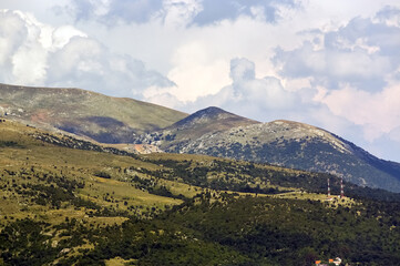 Obraz na płótnie Canvas Górskie szczyty porośnięte roślinnością na tle zachmurzonego nieba w pięknym oświetleniu