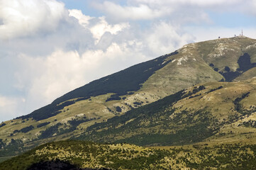 Fototapeta premium Górskie szczyty porośnięte roślinnością na tle zachmurzonego nieba w pięknym oświetleniu 