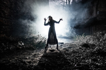 A young witch dances and conjures on Halloween night in smoke and light at the festival of the dead.