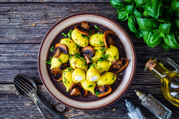 Gnocchi stuffed with cheese and fried white mushrooms on wooden table
