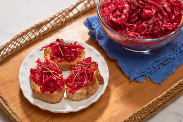 Homemade red cabbage sauerkraut ready to eat on rustic wooden shawl.