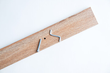 Metal silver furniture screw and wrench screwdriver and wooden board on white background.