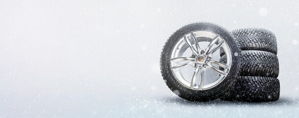 a set of winter tires and alloy wheels on a snowy white background. driving safety in winter and seasonal tire change in icy conditions - obrazy, fototapety, plakaty