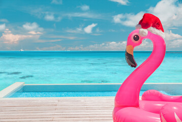 Christmas beach summer vacation flamingo pool float with santa hat travel background for winter holidays. - obrazy, fototapety, plakaty