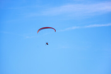 Colorful powered paraglider against blue sky. Paragliding concept, horizontal photo