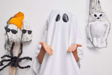 Photo of scarying ghost covered with white sheet gestures with hands tries to explain something...