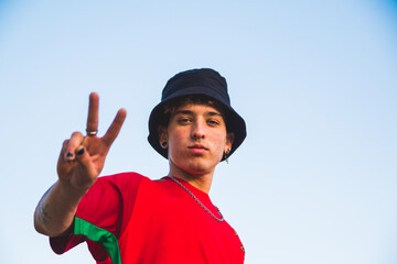 Portrait of a cool young Argentine boy showing the piece sign with painted nails outdoors © Leo Lascher/Wirestock