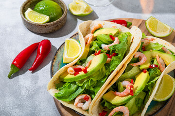 Traditional Mexican fast food. Mexican shrimp and avocado tacos with lime and spice peppers close up, trending sunlight