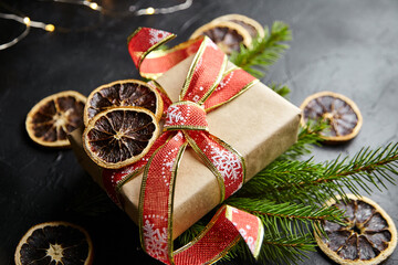 Christmas gift box with light garland and pine branches with dried orange fruit