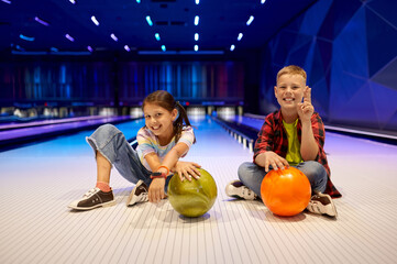 Children sitting on the lane in bowling alley - obrazy, fototapety, plakaty