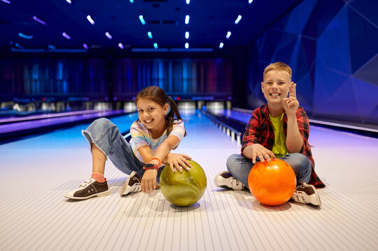 Children sitting on the lane in bowling alley