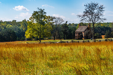 Old house in a colorful field with a blue sky in the fall