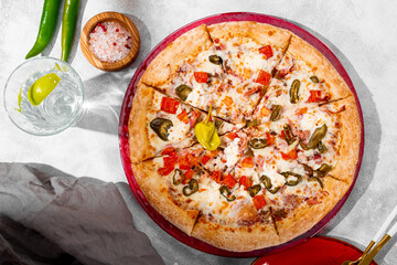 Spicy pizza with chicken, tomatoes and jalapenos on the light gray background top view
