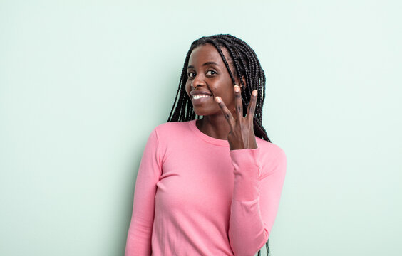 black pretty woman smiling and looking friendly, showing number three or third with hand forward, counting down